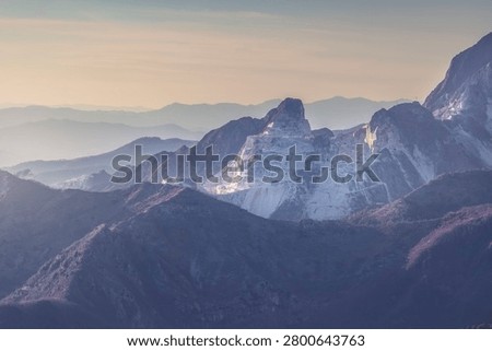 Panoramic twilight view of the white marble quarries cut into the majestic peaks of the Apuan Alps mountain range at sunset. Carrara, Tuscany, Italy