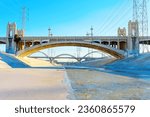 Panoramic view of the 6th Street Bridge spanning the LA River, with powerlines creating a dramatic urban skyline.