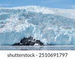 Panoramic view of Aialik Glacier in ocean bay with floating ice and icebergs connected to Harding Icefield near Kenai Fjords National Park in Seward, Alaska