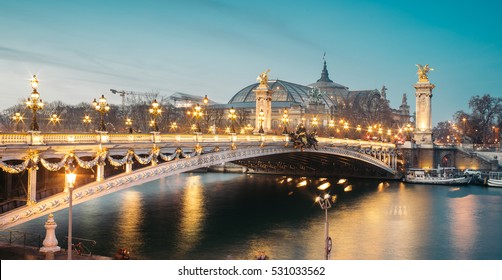 Panoramic view of the the Alexander III Bridge at dusk with Grand Palais (Great Palace) on the background. It's a deck arch bridge, regarded as the most ornate, extravagant bridge in the city. 