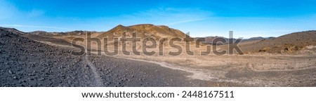 Panoramic view from Askja volcano in the lifeless volcanic desert in Highlands, with stones and rocks thrown by volcanic eruptions, Iceland, summer, blue sky.
