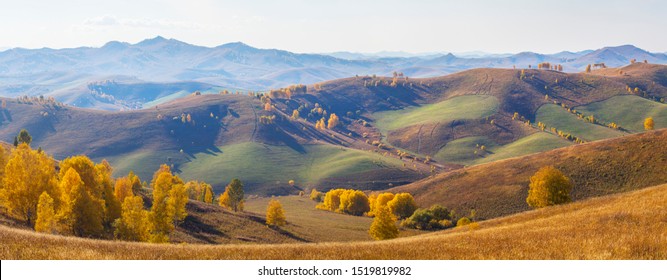 Panoramic view, autumn. The picturesque valley. Forested slopes and mountains in the distance in a blue haze.