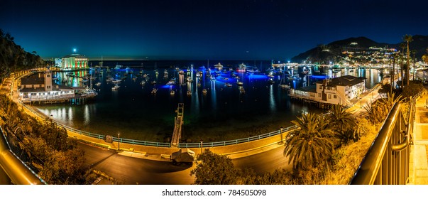 Panoramic view of Avalon City Casino lights and ocean bay full of yachts on Catalina Island at night.