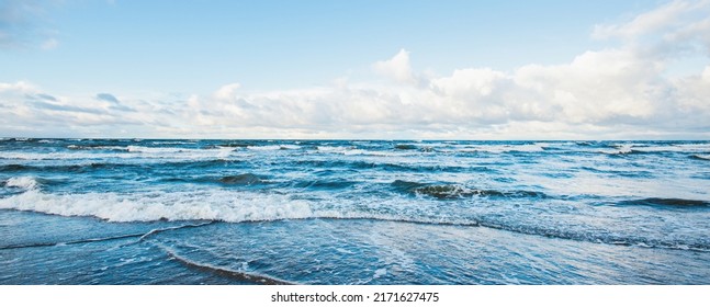 Panoramasicht auf die Ostsee von einem Sandstrand (Sanddünen). Dramatischer Himmel mit dunkelblühenden Wolken. Wellen, Wasser spritzt. Idyllische Jahreszeit. Warmes Winterwetter, Klimawandel, Natur