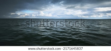 Panoramic view of Baltic sea from sandy shore (sand dunes) during the storm. Dramatic sky with dark cumulus clouds. Waves, water splashes. Seascape. Weather, climate change, nature