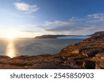 Panoramic view of bay at Eqi Glacier (Eqip Sermia) in Greenland north of Ilulissat during sunset with golden hour colours.