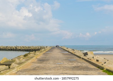 Panoramic view of a beautiful curvy footpath going towards a lighthouse at Scheveningen Beach located on the coast of North Sea in The Hague, Netherlands. Photograph clicked on a sunny Summer day.