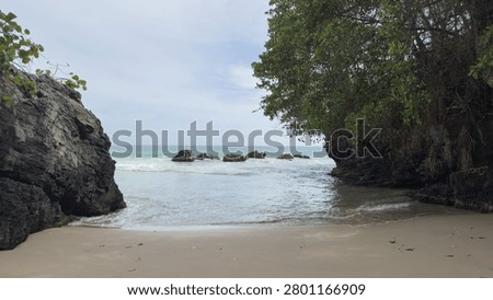 Panoramic view of a beautiful, secluded sandy beach, framed by towering rocky cliffs and lush green trees