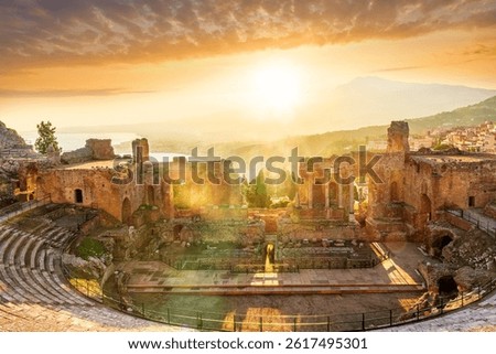 Panoramic view of a beautiful sunset in Ancient Theatre of Taormina in Sicily with antique italian town and mountain sunset on background. Holidays and sightseeing in Italy