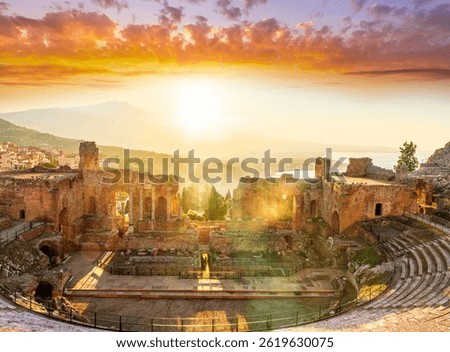 Panoramic view of a beautiful sunset in Ancient Theatre of Taormina in Sicily with antique italian town and mountain sunset on background. Holidays and sightseeing in Italy