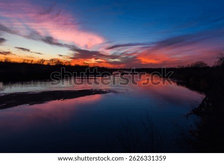 A panoramic view of a beautiful sunset with trees reflected in the Cimarron River in Oklahoma