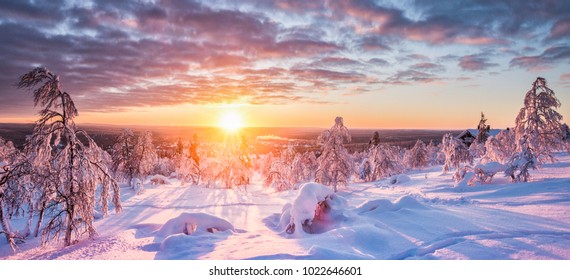 Panoramic view of beautiful winter wonderland scenery in scenic golden evening light at sunset with clouds in Scandinavia, northern Europe