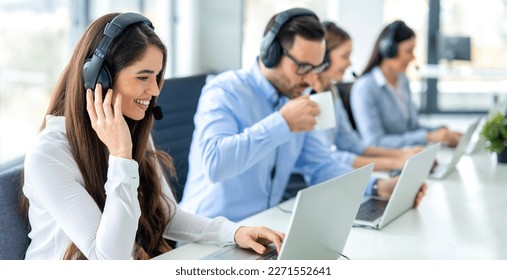 Panoramic view of beautiful young woman, customer service representative, working in call center with her colleagues using laptops. - Powered by Shutterstock