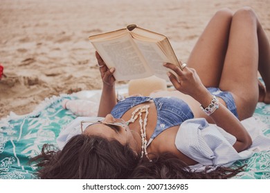 Panoramic View Black Indian Woman Lying On The Beach Reading A Book While Looking Forward On A Sunny Day. Summer Vibes Concept 2021.