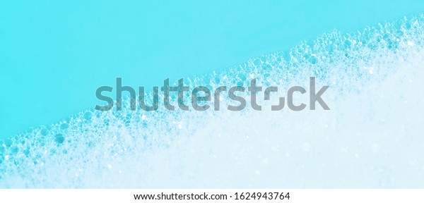 panoramic view of blue wet soap bubbles on blue\
background. Laundry detergent, suds textured pattern. White soap\
suds macro view. Abstract textured effect of blue soap foam\
close-up. divided\
frame