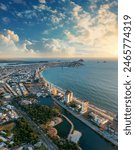 Panoramic view of the boardwalk and bay of Mazatlán, with a sky filled with abundant sunset clouds, and partial view of the city