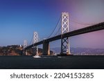 Panoramic view of boat passing through San Francisco - Oakland Bay bridge with clear blue sky.
