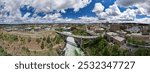 A panoramic view of a bridge spanning the Spokane River in Spokane, WA, showcasing its architectural beauty against the backdrop of the flowing river and surrounding lush greenery.