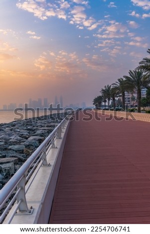 Panoramic view of the business bay, the downtown area of Dubai and two arab men take a walk on the promenade a cloudy day in UAE