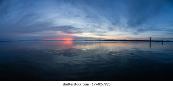 Panoramic View of the Calm Water on the Pacific Ocean Coast during a colorful cloudy sunset. Taken in White Rock, Vancouver, British Columbia, Canada.