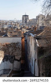 A panoramic view captures the charming rooftops of an old European city, leading up to a prominent cathedral and a distant Ferris wheel under a clear sky.