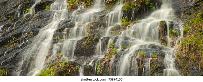 Panoramic view of Catawba Waterfall in Western North Carolina in the spring with fresh green on the rocks under the falls.