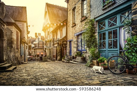 Panoramic view of a charming street scene in an old town in Europe in beautiful evening light at sunset with retro vintage Instagram style pastel toned filter and lens flare sunlight effect in summer