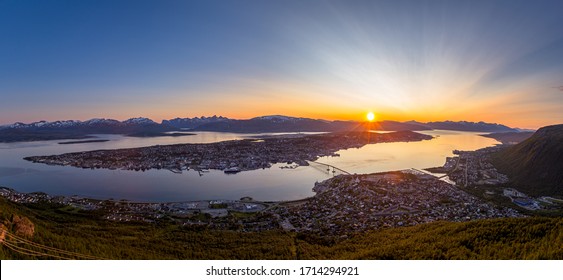 Panoramic view of the city of Tromso, located above the arctic circle in Norway. Various city landmarks are visible, with the midnight sun setting behind the landscape in the background. - Shutterstock ID 1714294921
