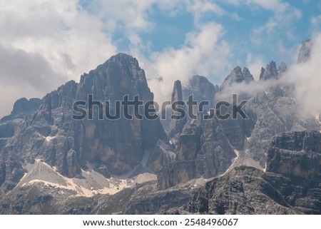 Panoramic view of cloud covered rocky rugged mountain peaks of majestic Brenta Dolomites, Trentino, Italy. Wanderlust in alpine wilderness. Hiking in pristine Italian Alps in summer. Peace tranquility