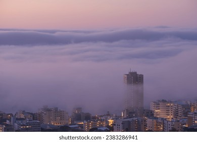 Panoramic view of clouds covering buildings at sunset in the popular city of Cape Town, South Africa with copy space. A peaceful, misty sunrise over signal hill. Landscape of a modern town at night