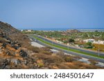 Panoramic view to coastline landscape of North Emirates countryside, oasis with developing agriculture industry and winding highway road, Dibba-Khorfakkan-Fujairah, UAE.
