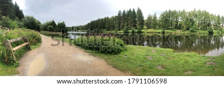 Panoramic view of the Cod Beck reservoir close to Osmotherley village in the north east of England, north Yorkshire moors. A wooden bench is on the left hand side. A walking trails is seen.
