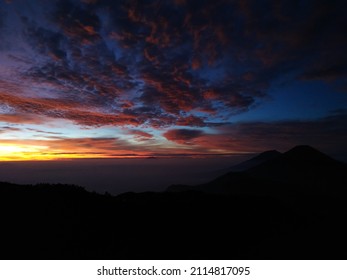 Panoramic view of colorful sunrise over misty mountains on natural nuance background of forest and mountain silhouettes