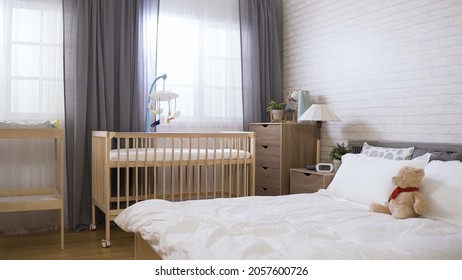 Panoramic View Of A Contemporary Bright Organized Bedroom Equipped With A Baby Bed And A Diaper Change.