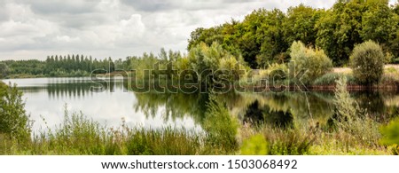 Panoramic view of a Cotswold lake with reflections.