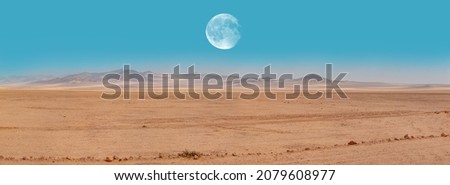Panoramic view of desert plains in Namibia Africa with hills and mountains in the background - Full moon on the mountains