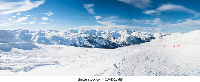 Panoramic view down snow covered valley in alpine mountain range on blue sky background - Powered by Shutterstock