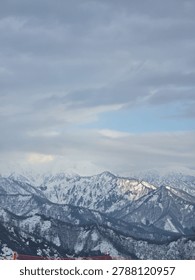Panoramic view of dramatic snow-covered mountain range under a cloudy winter sky