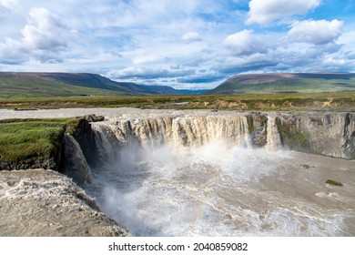 Panoramic view from the Eastern bank of the Godafoss waterfall in Iceland which runs through the Bardardalur valley: light rainbow visible