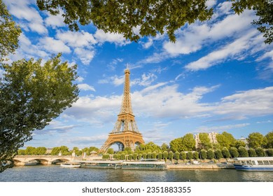 A panoramic view of the Eiffel Tower against a background of blue sky and beautiful clouds and the Seine River on a sunny day in Paris. France