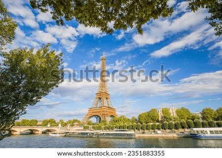 A panoramic view of the Eiffel Tower against a background of blue sky and beautiful clouds and the Seine River on a sunny day in Paris. France