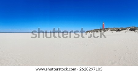 Panoramic view of an empty beach with a red lighthouse