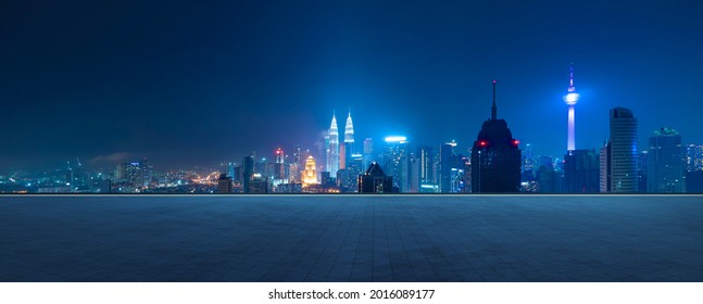 Panoramic view of empty concrete tiles floor with city skyline. Night scene.