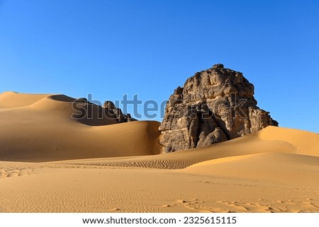 Panoramic view of empty Sahara desert with blue sky, rocks, sand and mountains in Tassili n'Ajjer national park in Algeria.