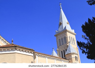 A panoramic view of the facade of St. Nicholas Cathedral in Da Lat, Vietnam, showcasing the main tower, side towers, and statue of the Virgin Mary. It displays the complete architectural structure of a French-style church, making it suitable for cultural tourism promotion, architectural photography, religious scenes, and city landmark illustrations.