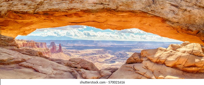 Panoramic view of famous Mesa Arch, iconic symbol of the American West, illuminated golden in beautiful morning light on a sunny day with blue sky and clouds, Canyonlands National Park, Utah, USA - Powered by Shutterstock