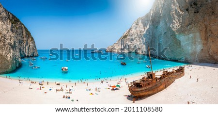 Panoramic view of the famous Navagio shipwreck beach on Zakynthos island, Greece, with people enjoying the light blue colored sea