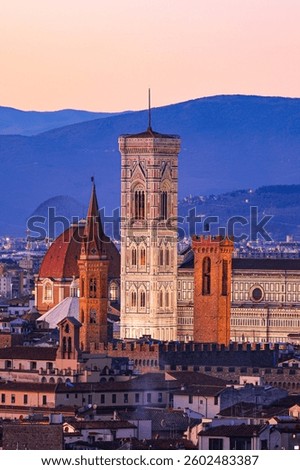 A panoramic view of Florence at sunset, featuring the Cathedral of Santa Maria del Fiore and its bell tower standing prominently in the city center, showcasing the charm of the Italian