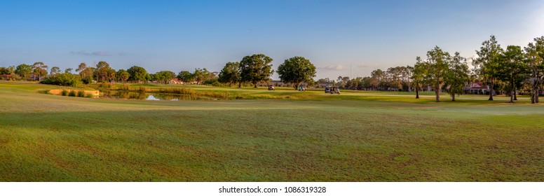 Panoramic view of golf course with golf carts at the distance