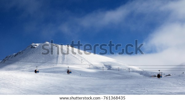 Panoramic view of gondola and chair lifts on ski\
resort at winter evening with snowfall. Caucasus Mountains,\
Georgia, region\
Gudauri.